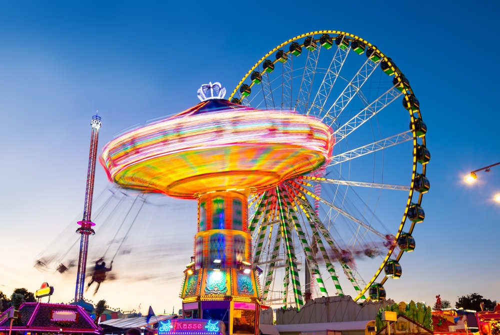 A Ferris wheel and other carnival rides are lit up as the sun sets. What to do if I’m injured at the Cabarrus County Fair?