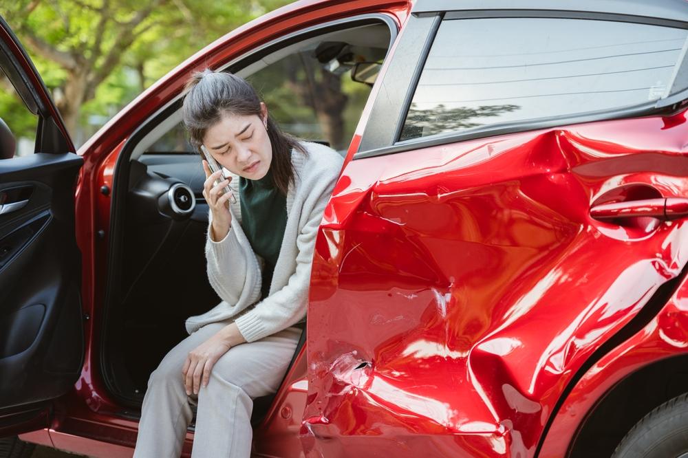 A woman views her car after an Amazon truck accident and calls to find out how to file a truck accident claim against Amazon.