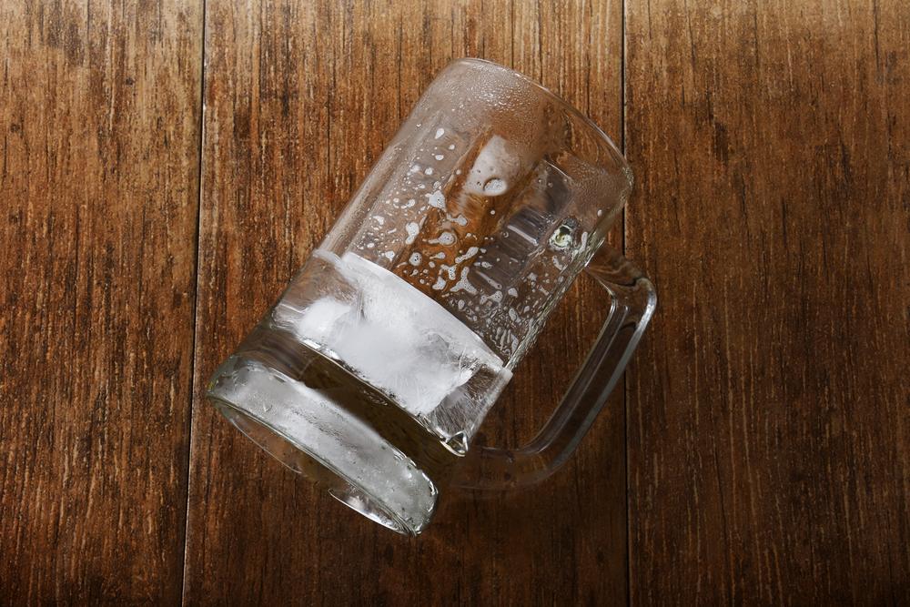 An empty glass of beer on a wooden counter in a bar that’s subject to the dram shop laws in North Carolina.