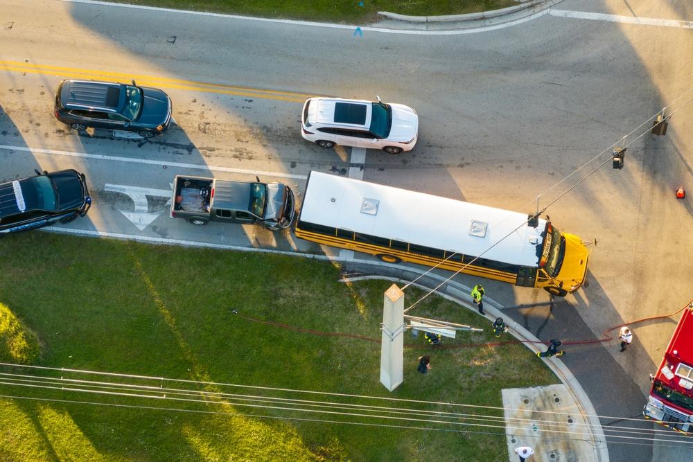 Law enforcement, firefighters, and first responders checking to see if any child was injured in a school bus accident on a road with other cars nearby.