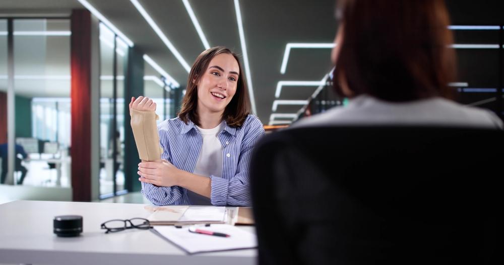 Lawyer sitting across from an injured woman at a desk, explaining to her what she should do after being hit by a car as a pedestrian.