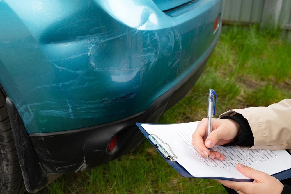 A law enforcement officer writes down information on a clipboard after a Raleigh car accident. How do I get a crash report in Raleigh, NC?