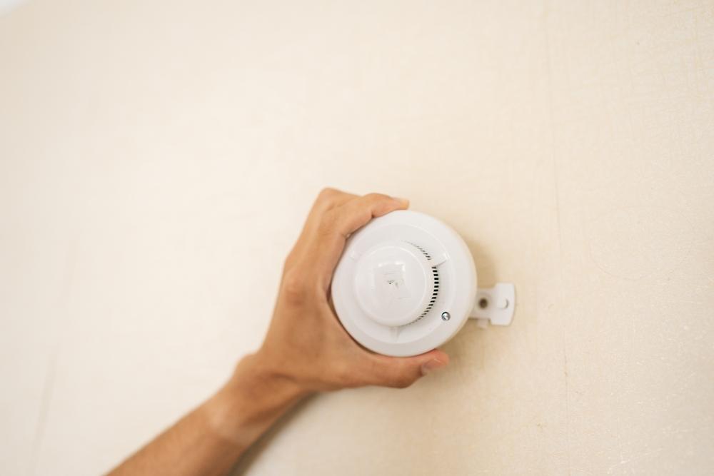 Person installs smoke alarm to stay safe and prepare for an apartment fire.