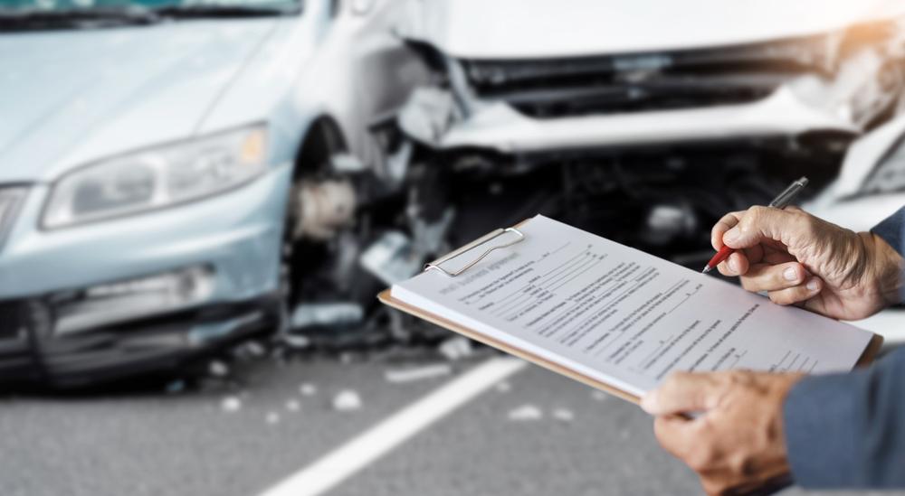 A man filling out a car accident report. A lawyer can explain how you get a crash report in High Point, NC.