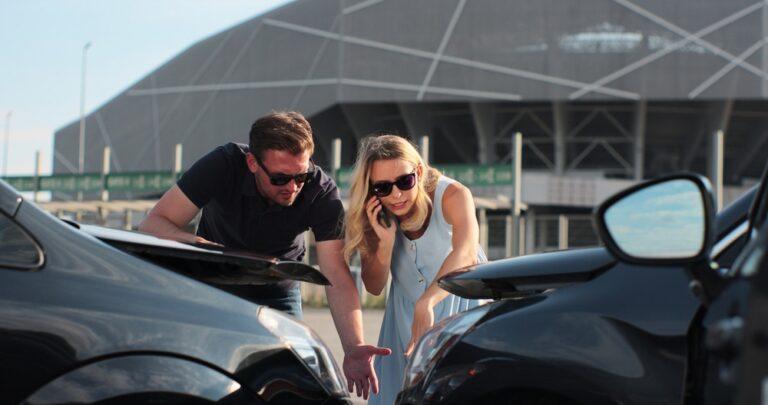 Two people at the scene of a car accident, with one person calling an insurance company about the incident and unsure of how to get a crash report in Winston-Salem, NC