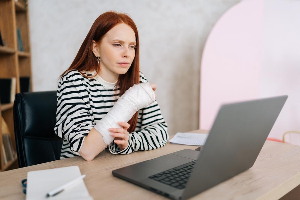An injured woman using her computer to research what to do if you’re injured at Greensboro Coliseum Complex.