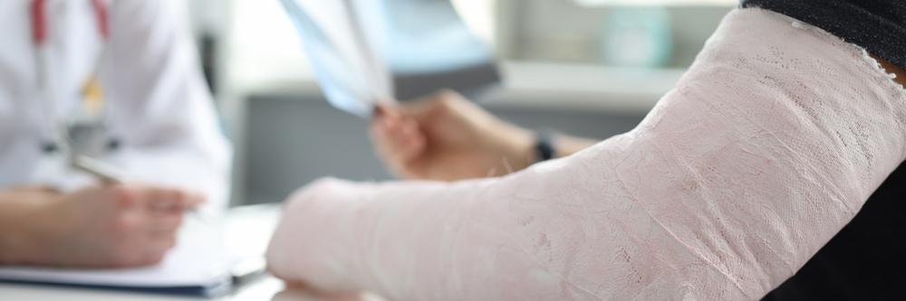 A person with a broken arm consulting a doctor. Learn about whether health insurance covers motorcycle accidents.