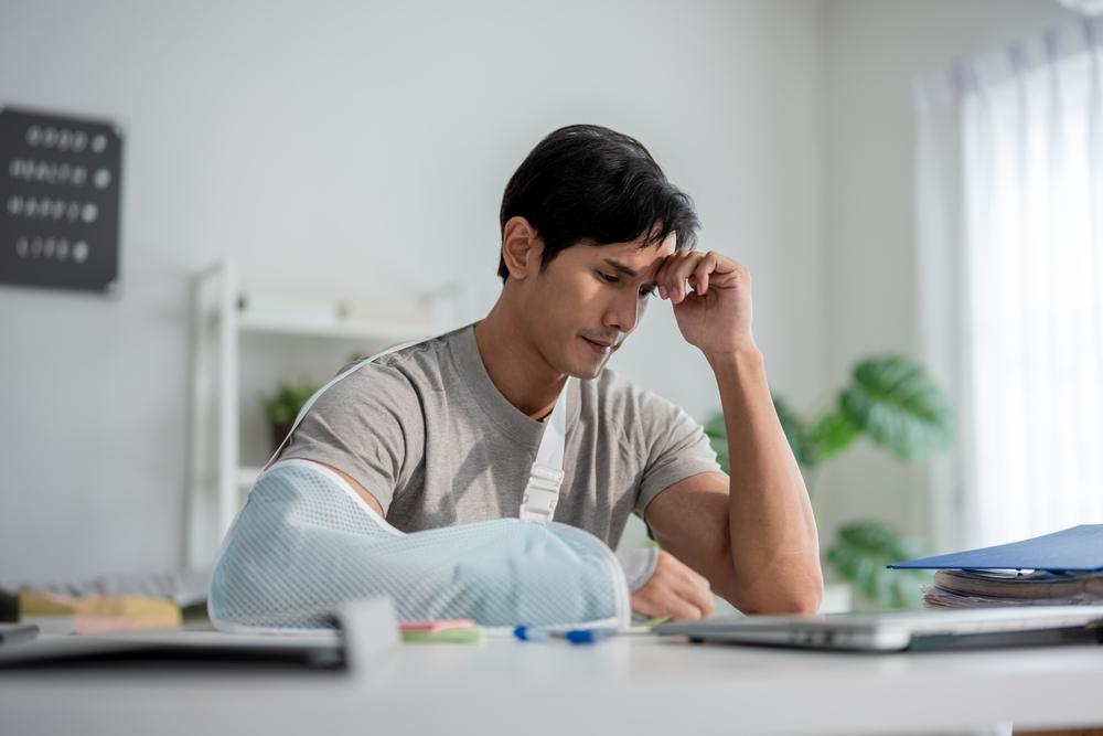 An injured man looks stressed at a desk. Motorcycle crashes in North Carolina are unfortunately common, but a lawyer can help after one.