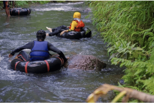 Two people float on an inflatable tube along a calm river. Tubing is a popular water activity, but serious injuries, such as broken bones, can occur.
