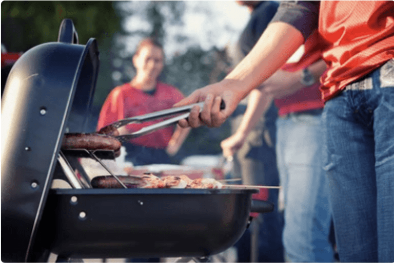 A man grilling sausages at a tailgate party. Football fans should know this season that their share of responsibility in a tailgating accident can impact the compensation they can recover.